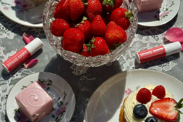 Strawberry lip balm labeled “Space Camp Strawberry Frosting” held close to a woman’s face.
