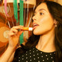 Woman applying Space Camp Salted Caramel lip balm in a retro-themed setting with festive decorations.