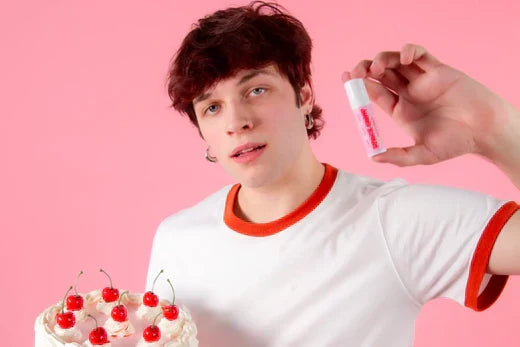 Person holding a lip balm tube and cherry cake, illustrating how to choose lip balm.
