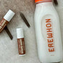 Space Camp Coconut Cream organic lip balms displayed alongside an Erewhon coconut milk bottle on a soft textured surface