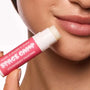 Lip care labeled Strawberry Frosting held near a woman's smooth, moisturized lips.