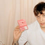 Best tinted lip balm Space Camp in pink packaging held by a young man in a white shirt.