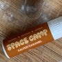 Lip balm for sensitive skin in Salted Caramel flavor displayed on a flour-dusted wooden surface.