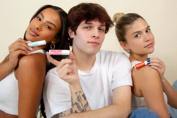 Lip balm collection held by three models, showcasing different flavors and vibrant packaging.