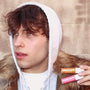 Natural lip hydration with salted caramel and wild cherry lip balms held by a stylishly dressed person in a fur-lined hoodie