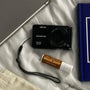 Organic lip balm with a salted caramel flavor displayed on a neatly arranged bed featuring a book, camera, and tablet.