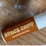Organic lip balm in a salted caramel flavor, placed on a wooden surface with scattered flour and a metal cookie cutter.