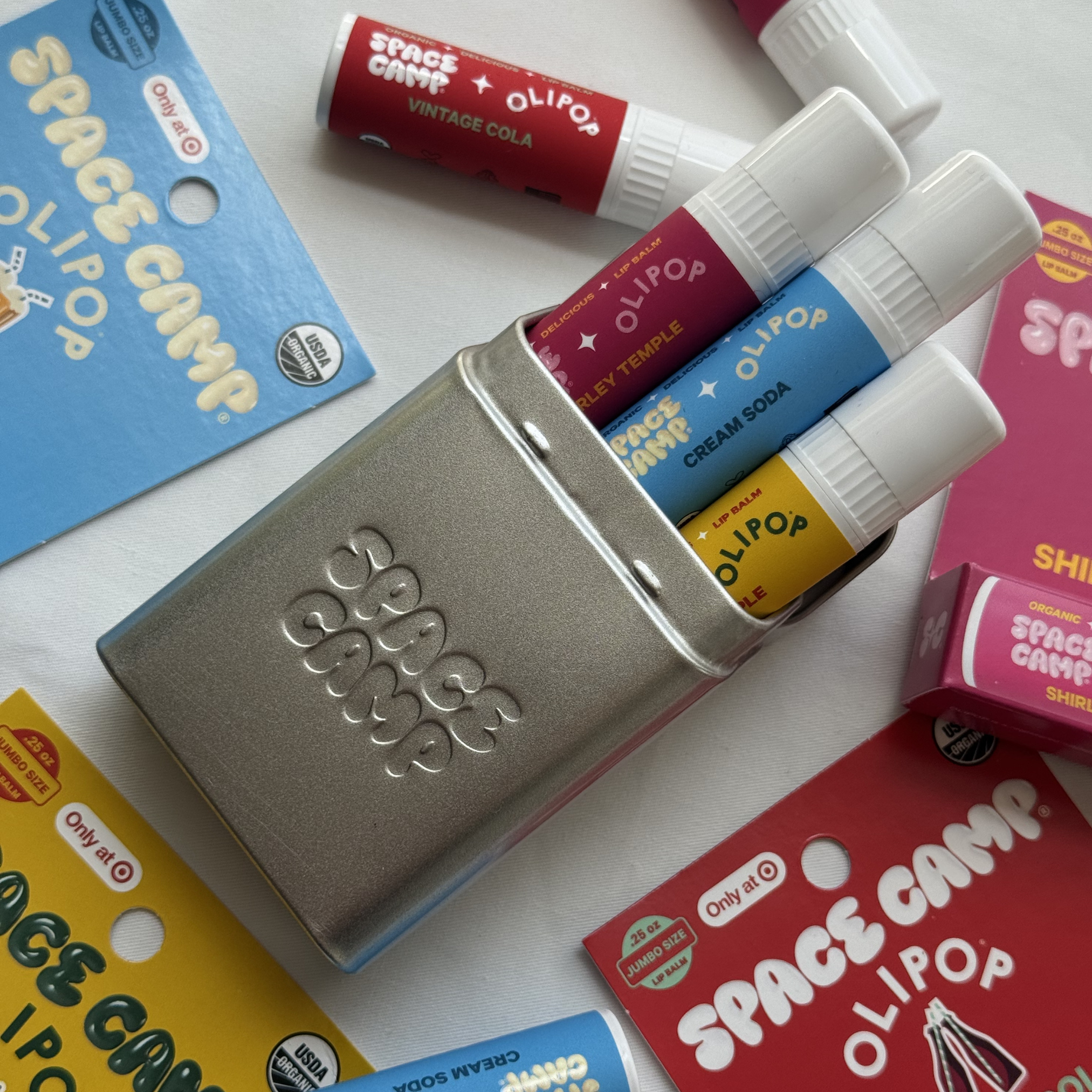 Space Camp x Olipop lip balm travel tin holding cola, cream soda, and cherry flavors.