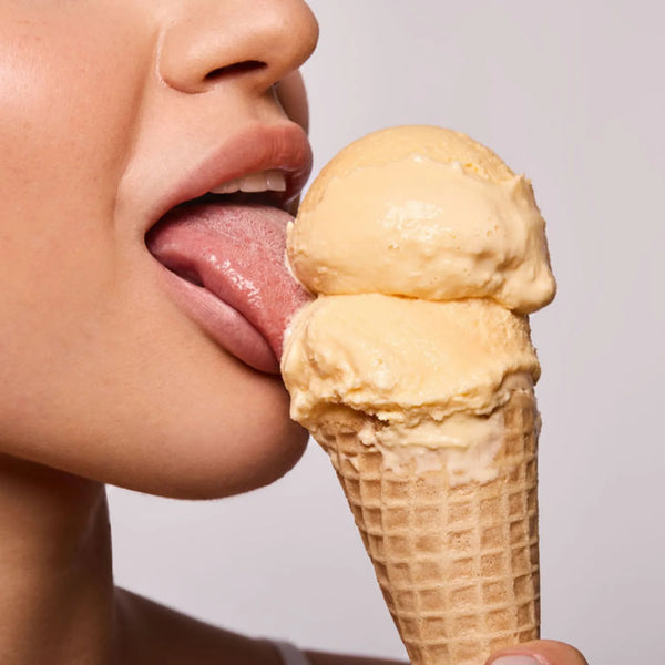 A close-up of a person licking a vanilla ice cream cone, evoking the sweet vanilla flavor.
