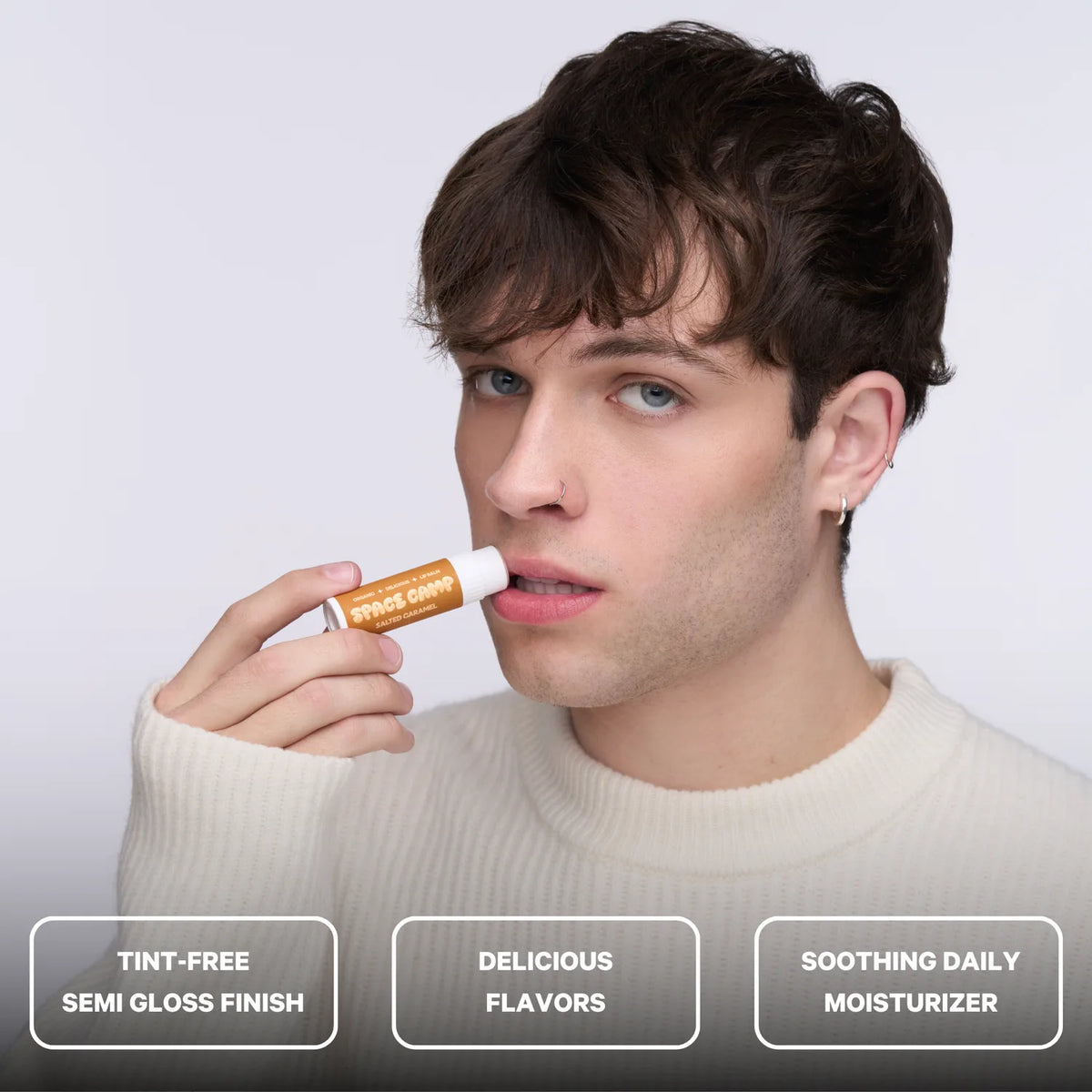 A person applying Space Camp Salted Caramel lip balm with feature callouts for tint-free finish, flavor, and daily moisturizer.