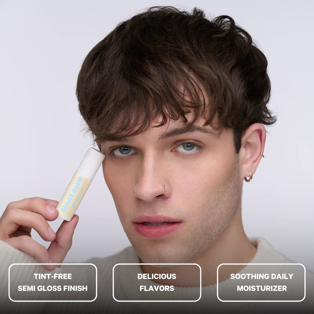 A person holding a Space Camp Birthday Cake lip balm with feature callouts for tint-free finish, flavor, and daily moisturizer.