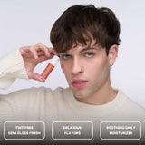 A person holding Space Camp Juicy Watermelon lip balm with feature callouts for tint-free finish, flavor, and daily moisturizer.