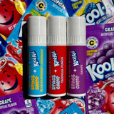 Three Kool-Aid flavored lip balms in Blue Raspberry Lemonade, Tropical Punch, and Grape on drink packets.